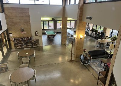 View of common area in Pleasant Valley Apartments with books, pool table, tables and chairs.