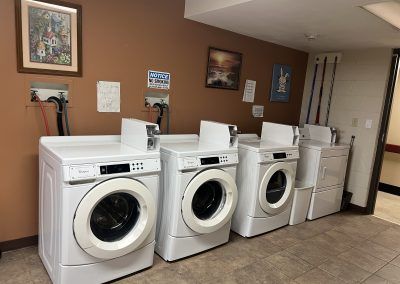 Three washing machines and a dryer in apartment building.