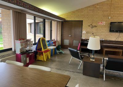Seating area with kids toys, seating, piano, and TV in apartment building common area.