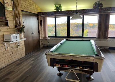 Pool table, windows, and microwave on a shelf in the main area of the housing building. Nice apartment building in Iron County.