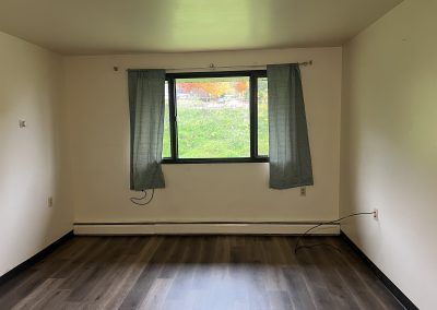 Pleasant Valley Apartment bedroom with laminate flooring and window with curtains in Crystal Falls, MI.